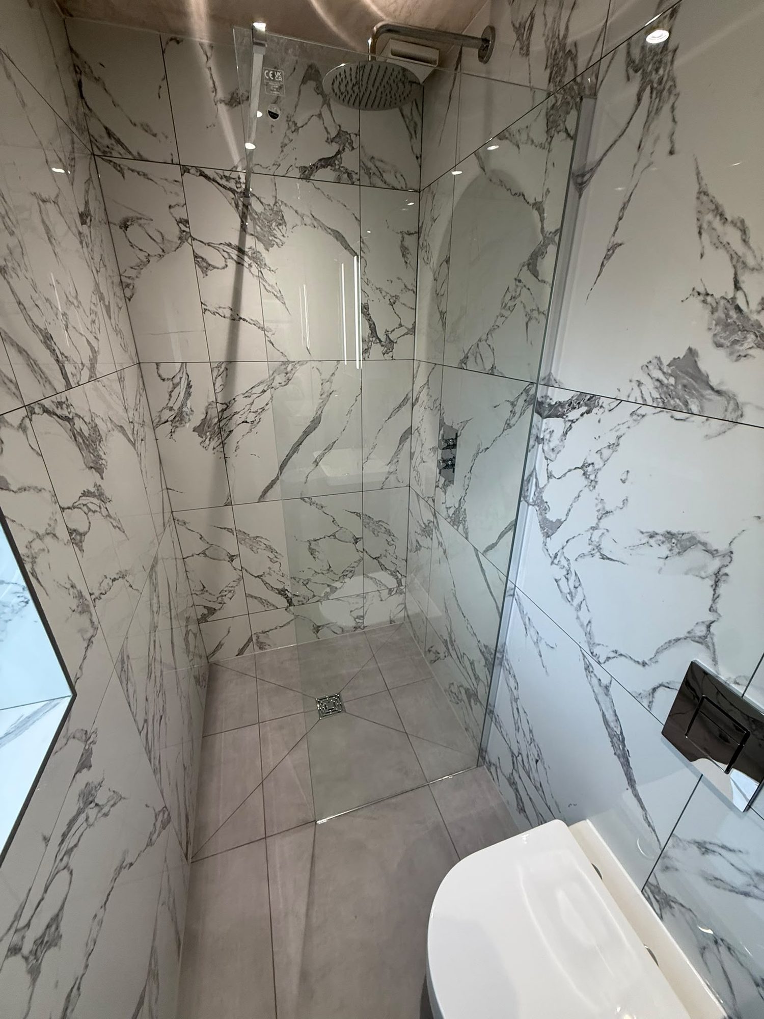 Walk-in shower with marble-effect tiling and concealed shower valve fitted by N Monk Plumbing & Heating
